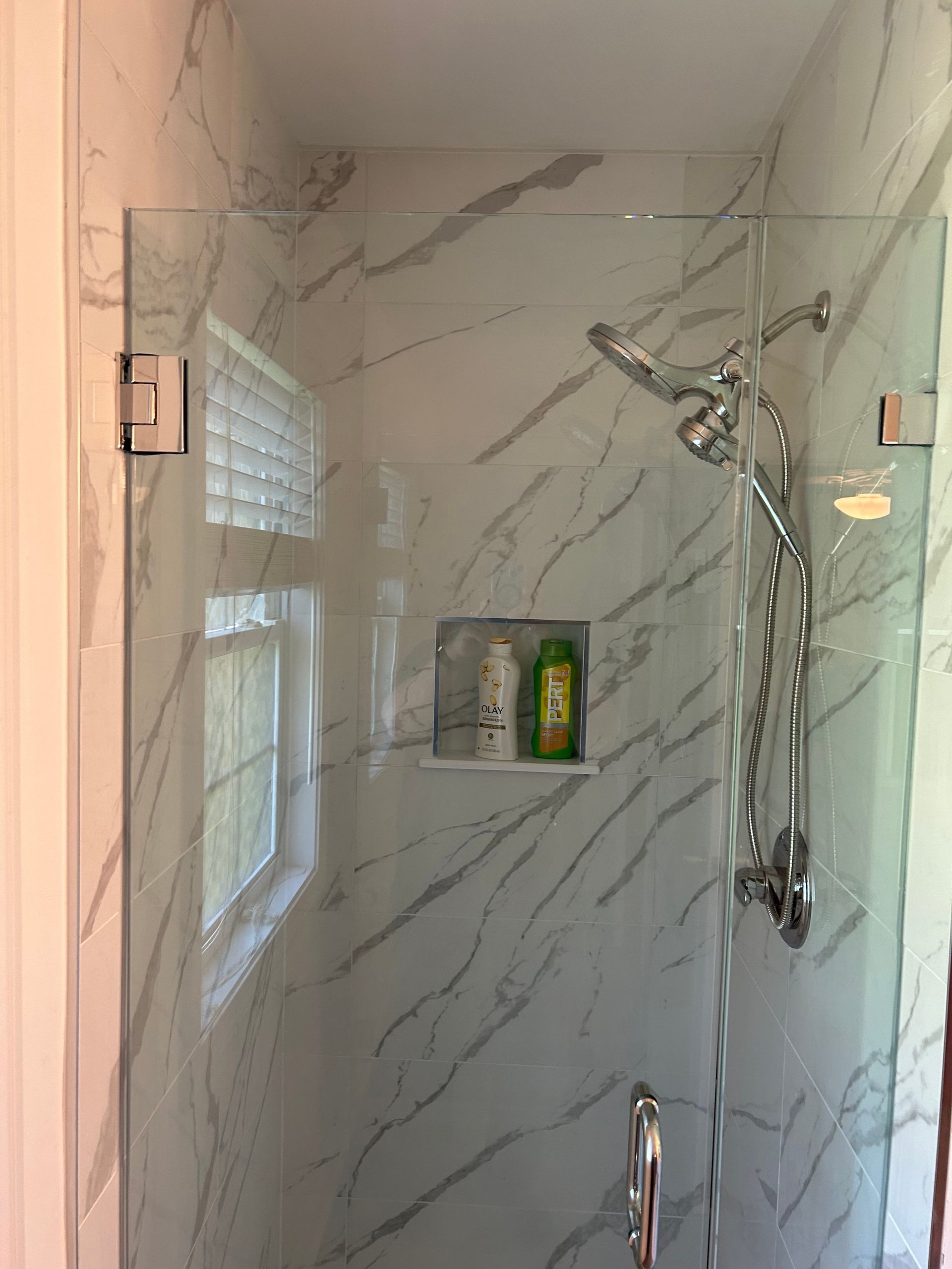 There is a shower with a glass door and a shower head.