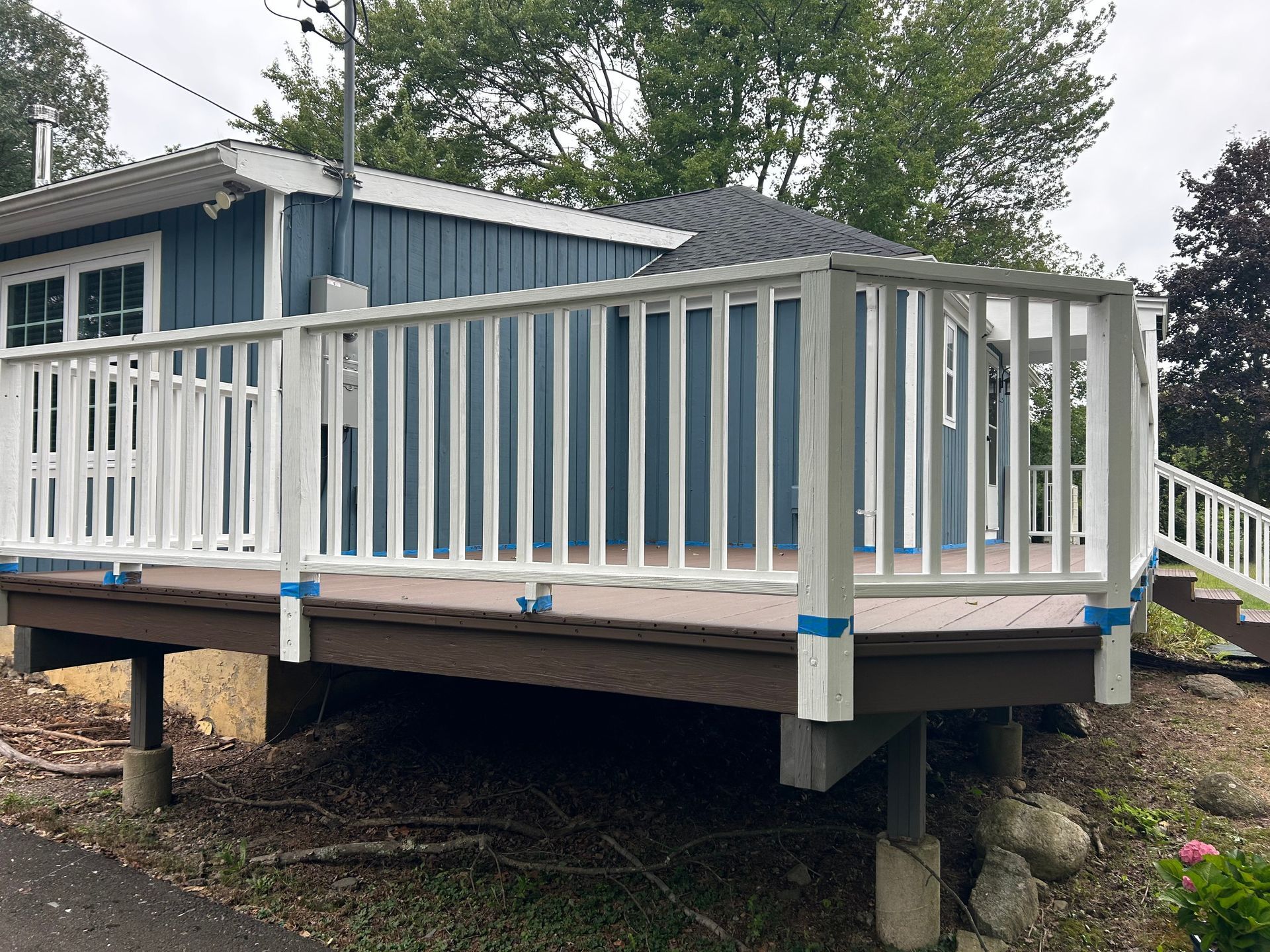 A blue house with a white deck and a white railing.