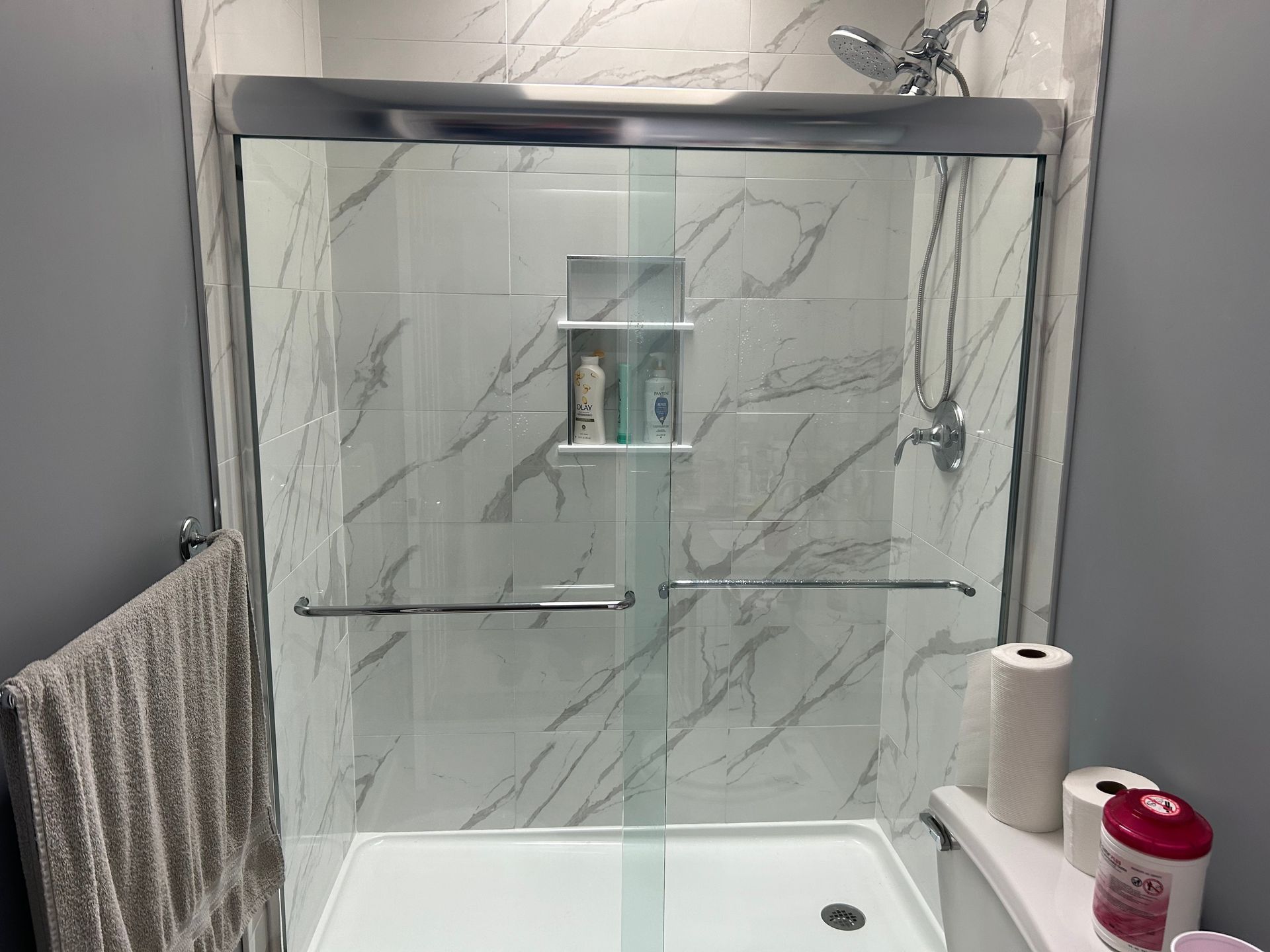 A bathroom with a sliding glass shower door and a toilet.