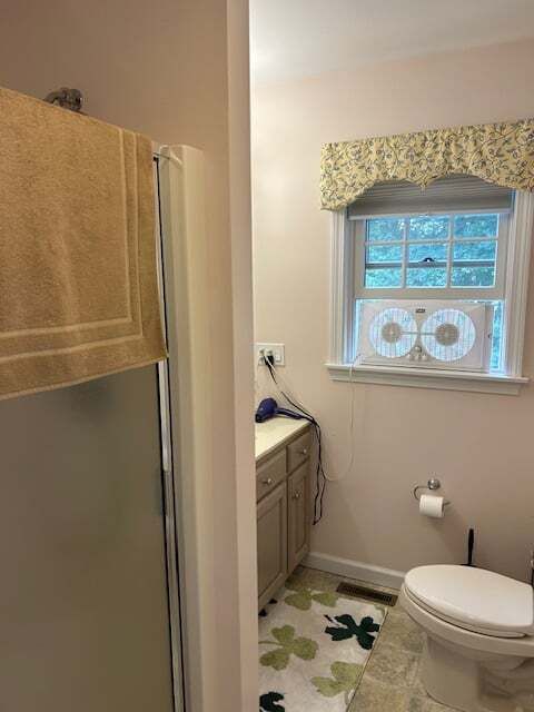 A bathroom with a toilet , shower and window.