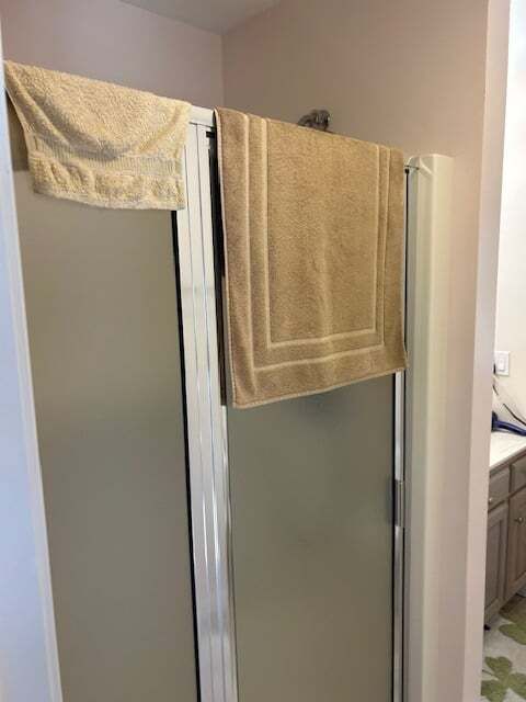Two towels are hanging on a shower door in a bathroom.