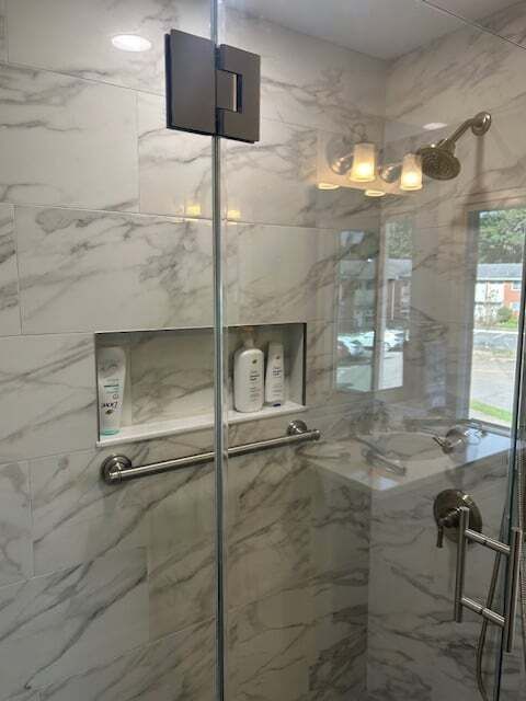 A bathroom with a walk in shower with a glass door.