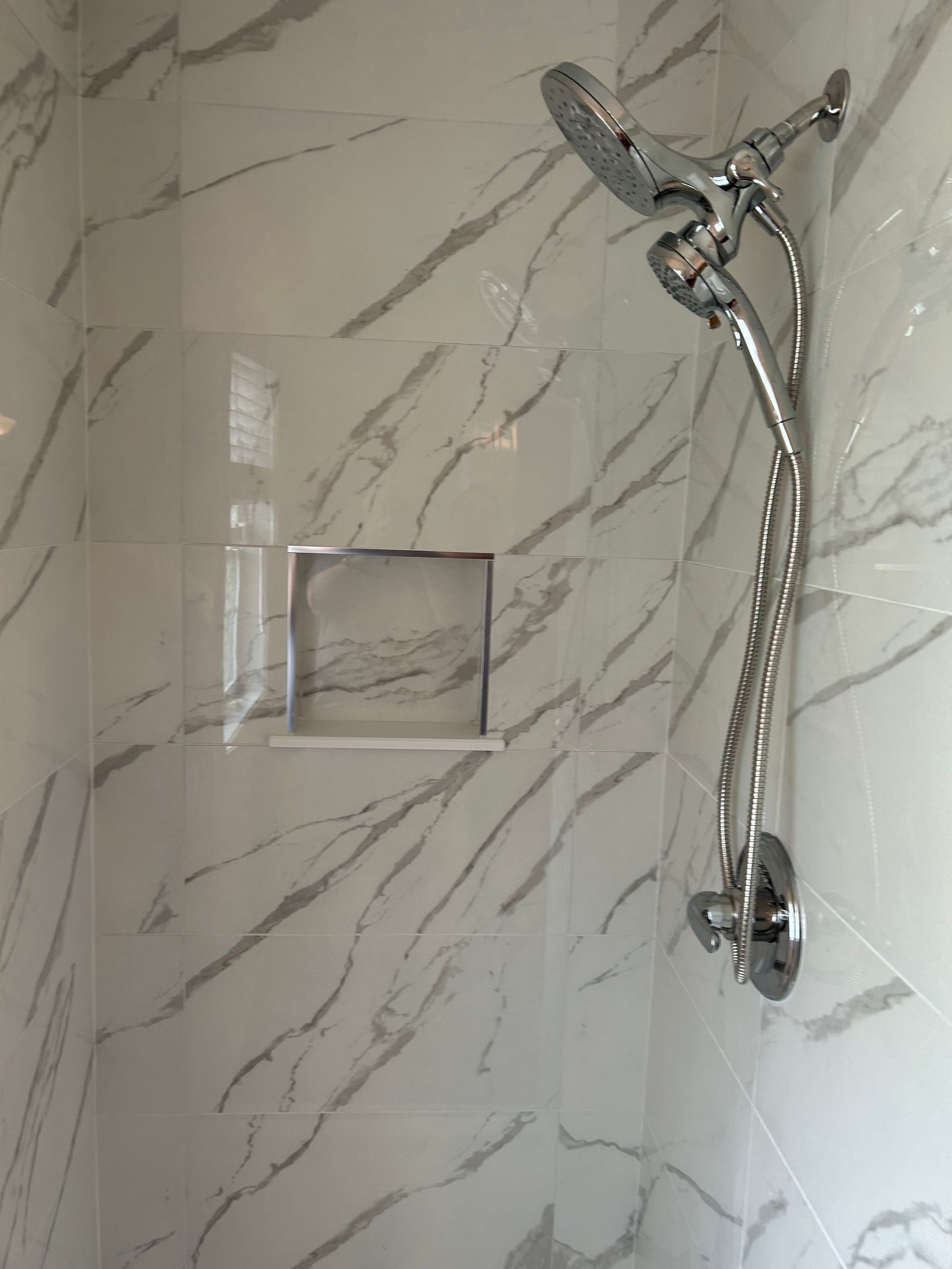 There is a shower head in the corner of the shower.