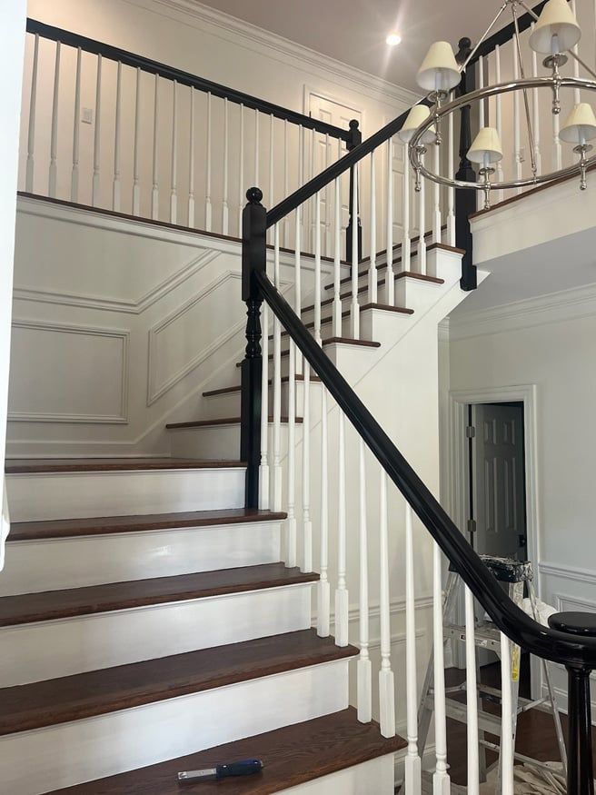 A white staircase with a black railing and wooden steps