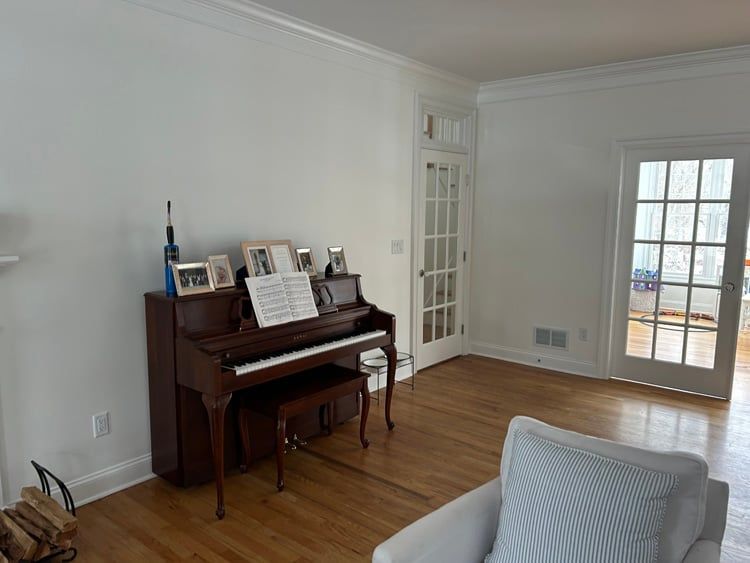 A living room with a piano and a chair.