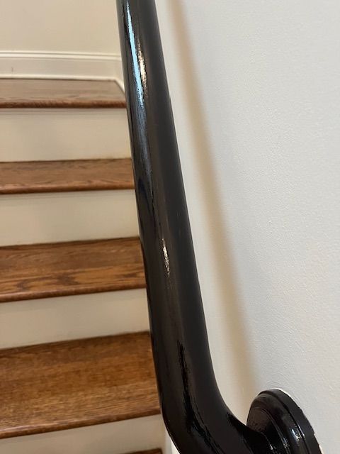 A close up of a black railing on a set of wooden stairs.