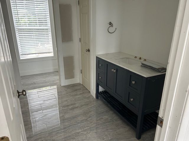 A bathroom with a vanity , sink , and window.