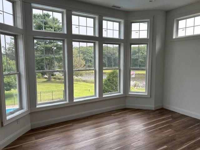 An empty room with a lot of windows and a wooden floor.