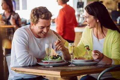 A man and a woman are sitting at a table in a restaurant eating food.