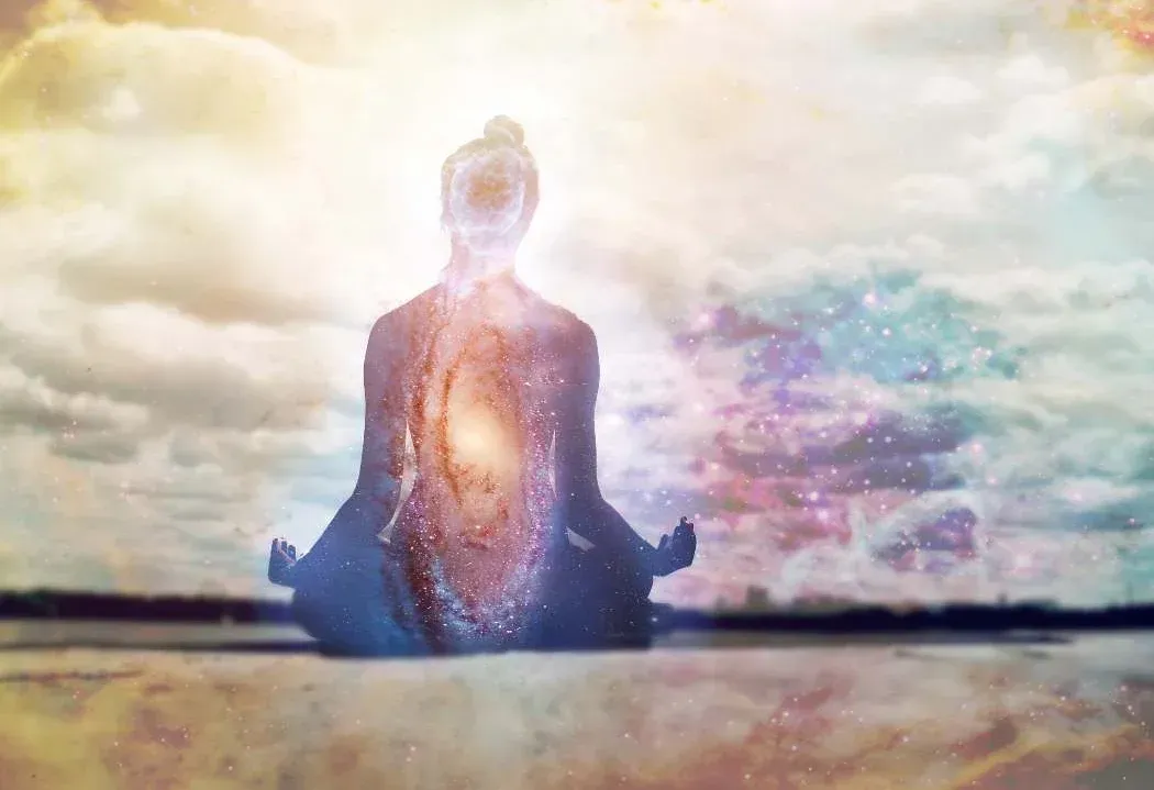 A person is sitting in a lotus position with a galaxy in the background.