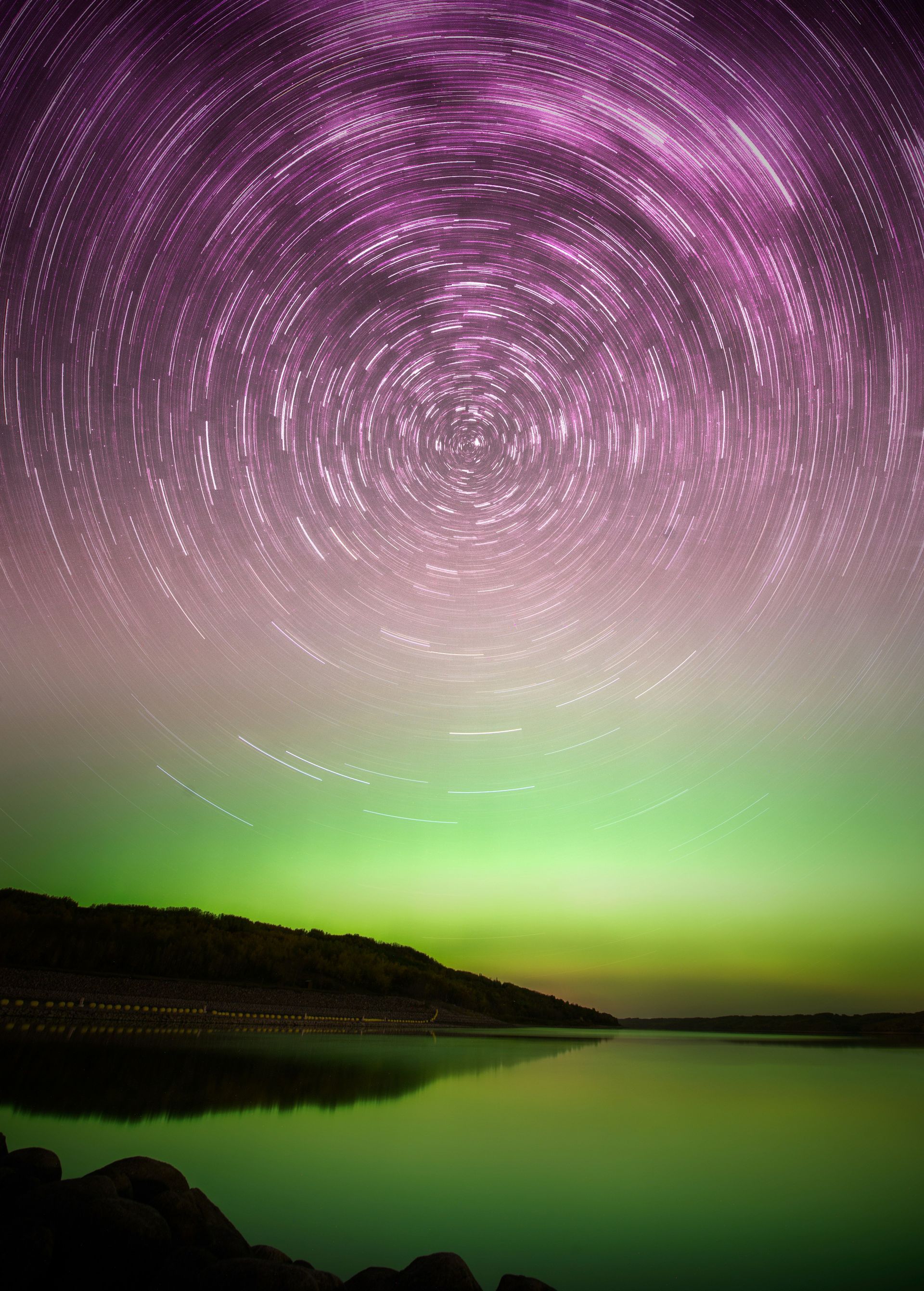 The aurora borealis is visible in the night sky over a lake.