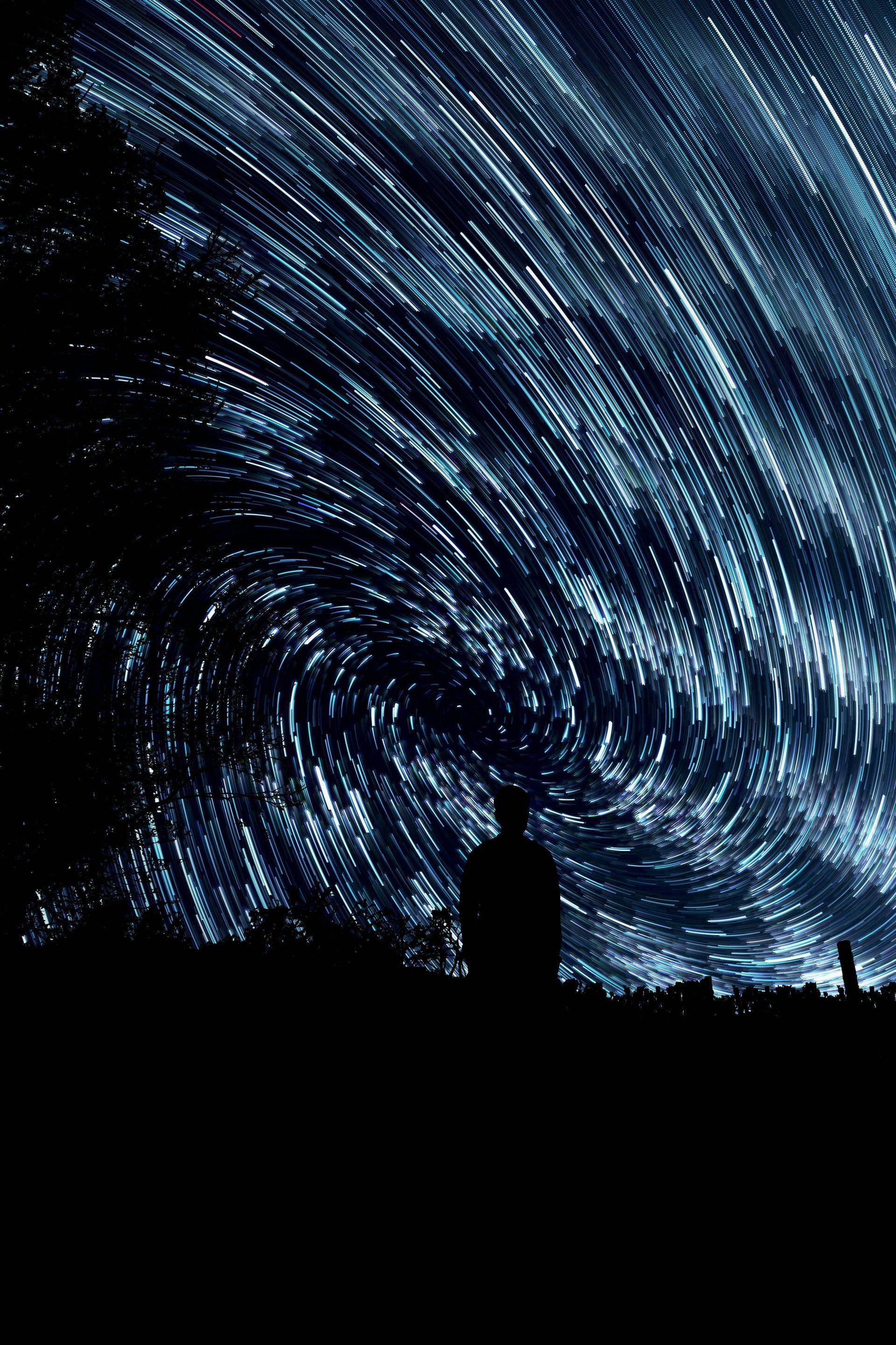 A man is standing in front of a starry night sky.