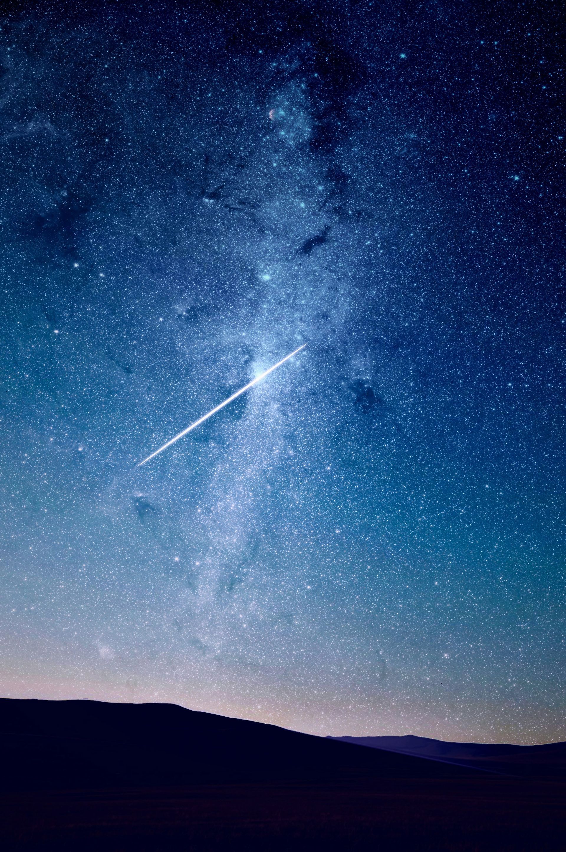 A breathtaking night sky filled with countless stars, featuring a bright meteor streaking across the Milky Way.