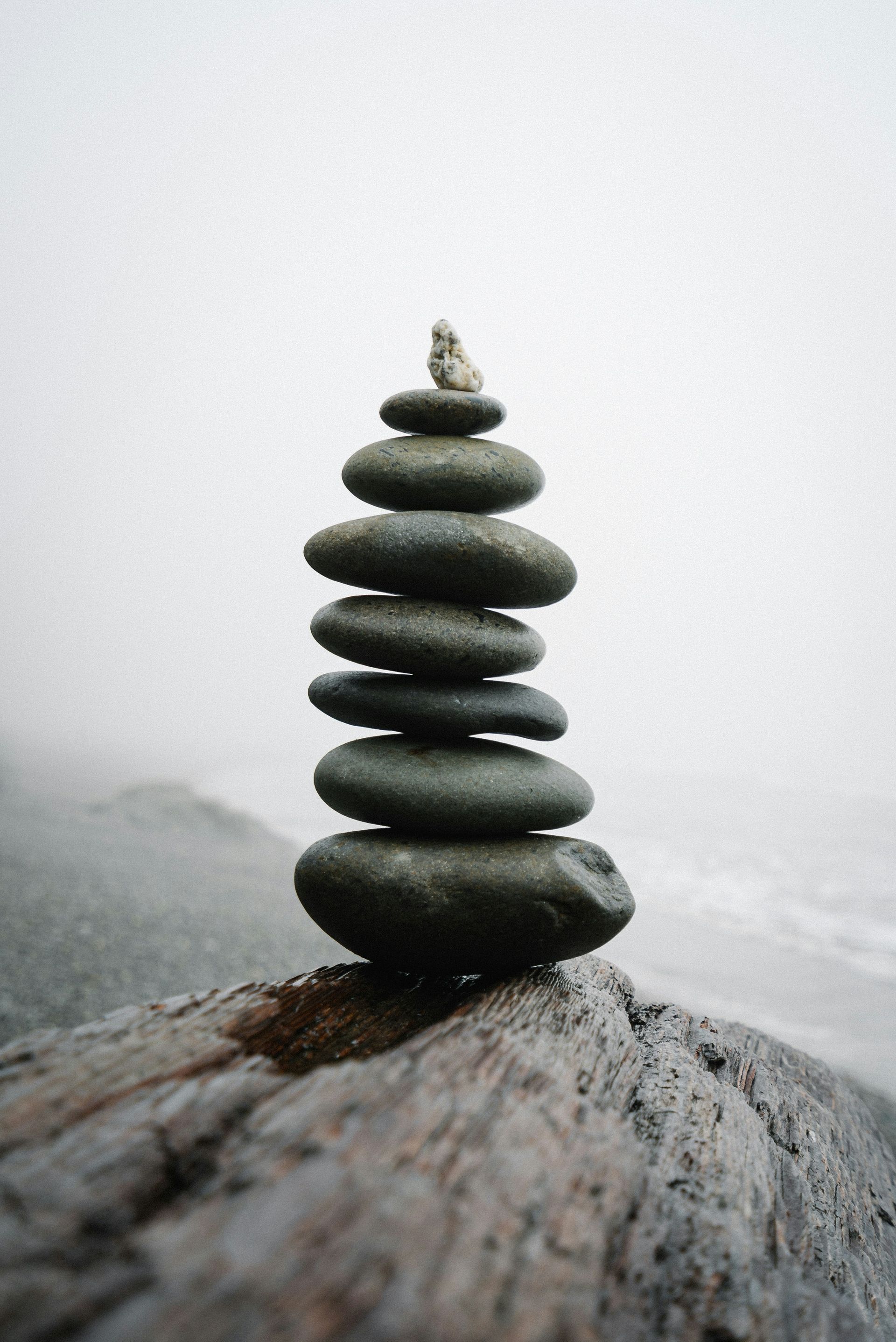 A stack of rocks sitting on top of a piece of driftwood.