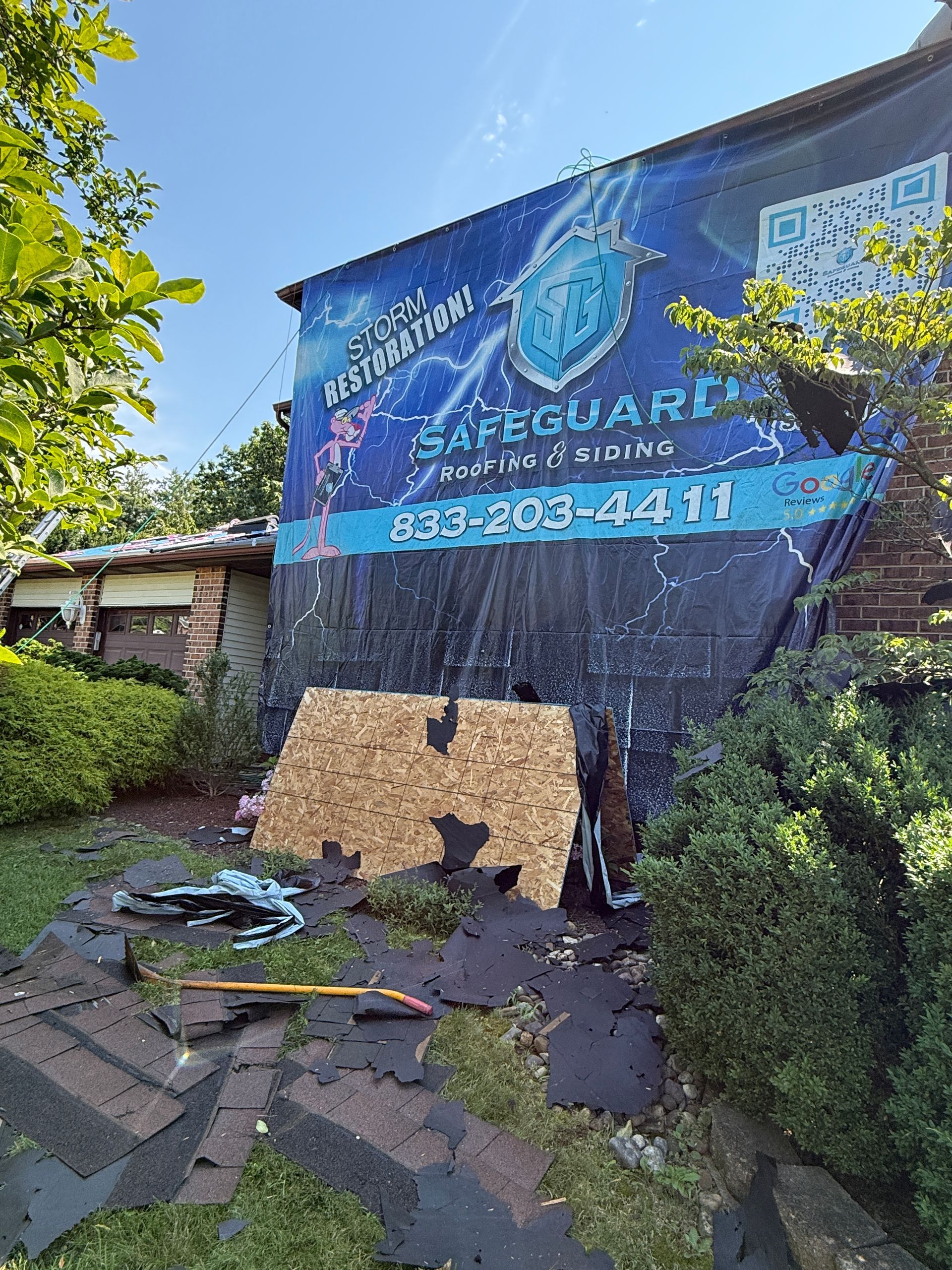 Damaged building with Safeguard banner. Shingles and debris on the ground.