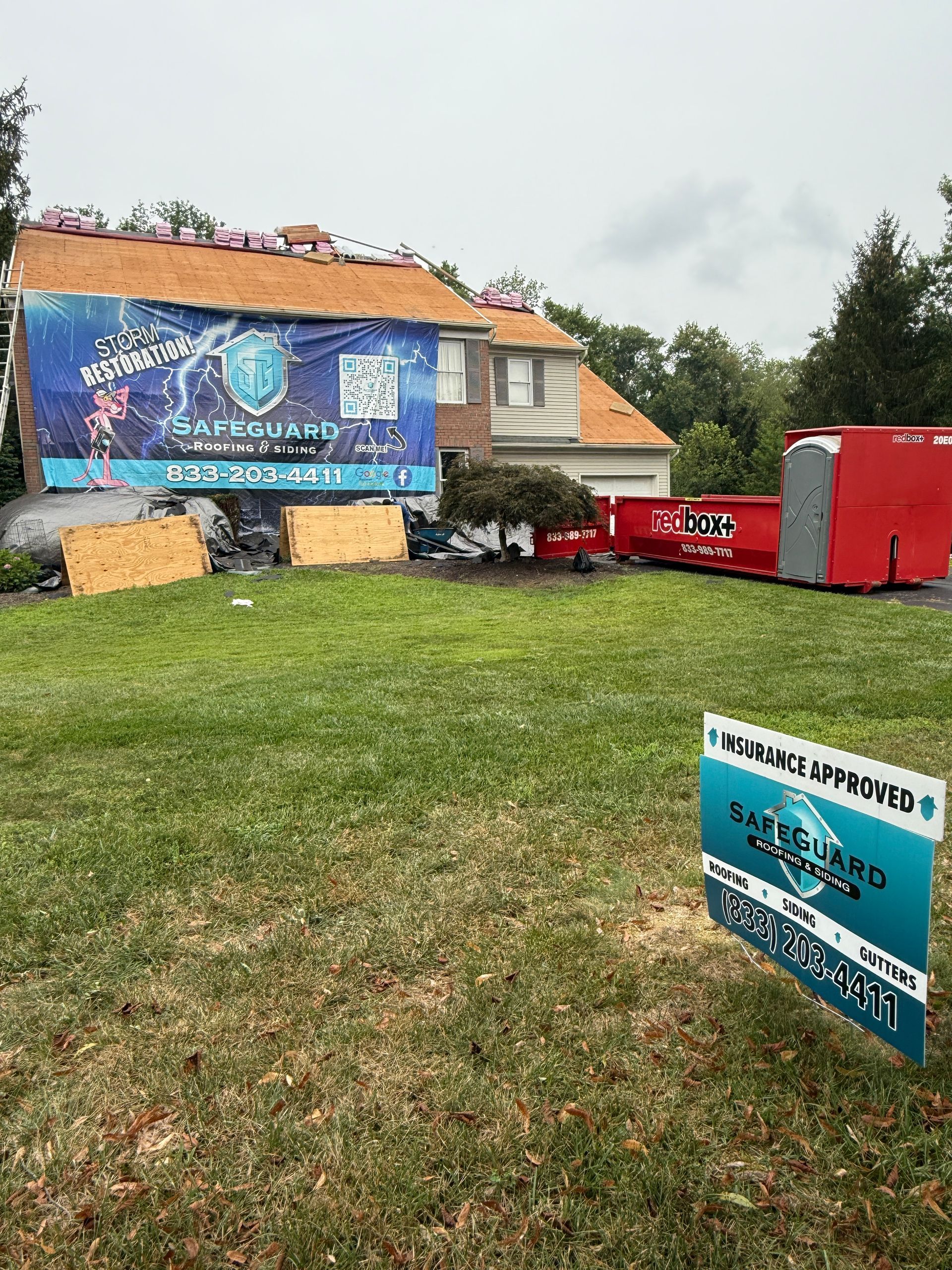 House with roof repair; Safeguard Roofing sign in yard, banner on the home, dumpster.