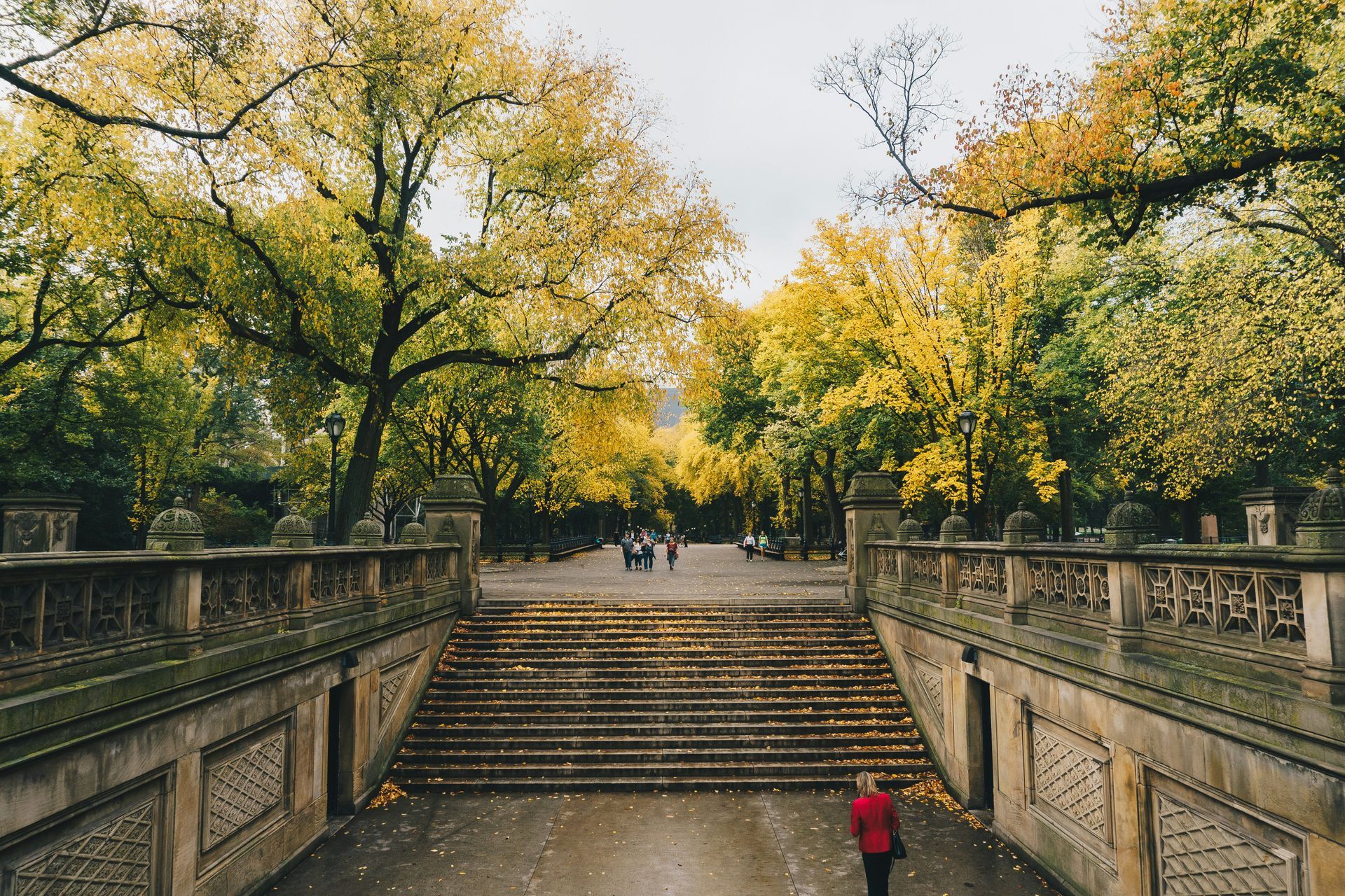 a woman climbs the stairs in NYC during the day as the leaves change