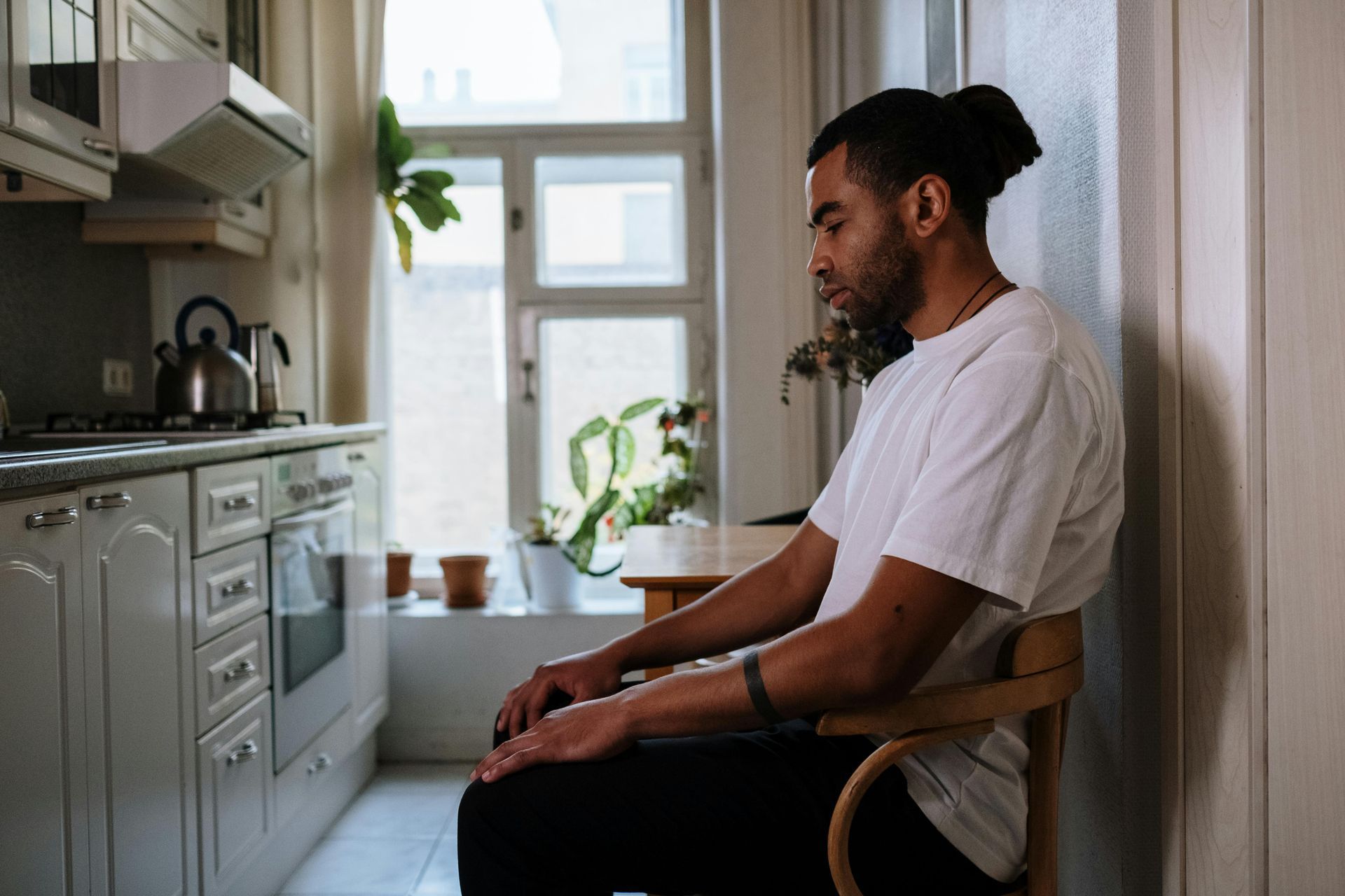 man sitting in a chair in his kitchen in New York City thinking of what to do about gf pregnancy