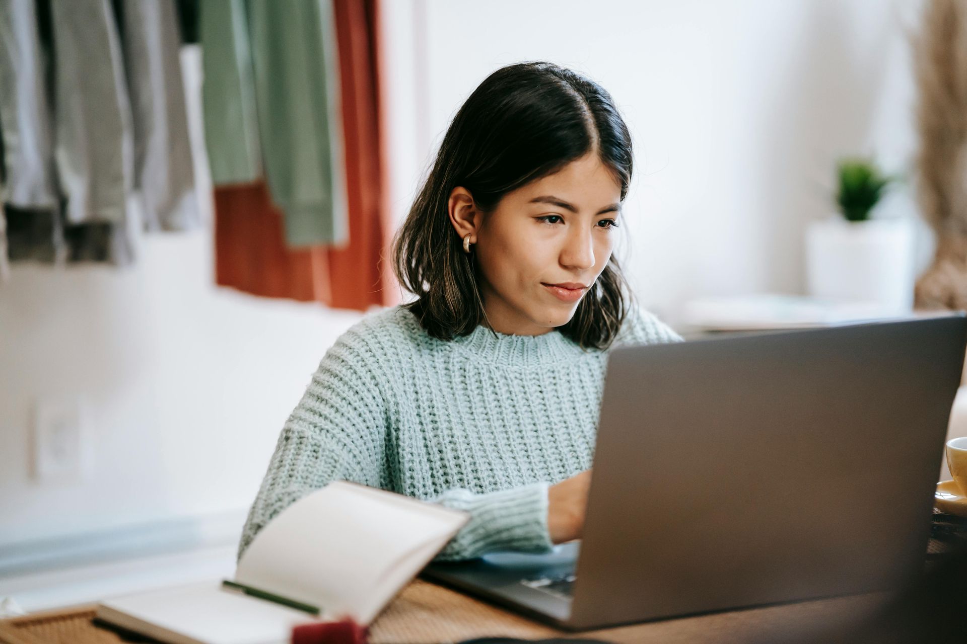 Latina woman in blue sweater uses her laptop to learn more about what to do for unplanned pregnancy