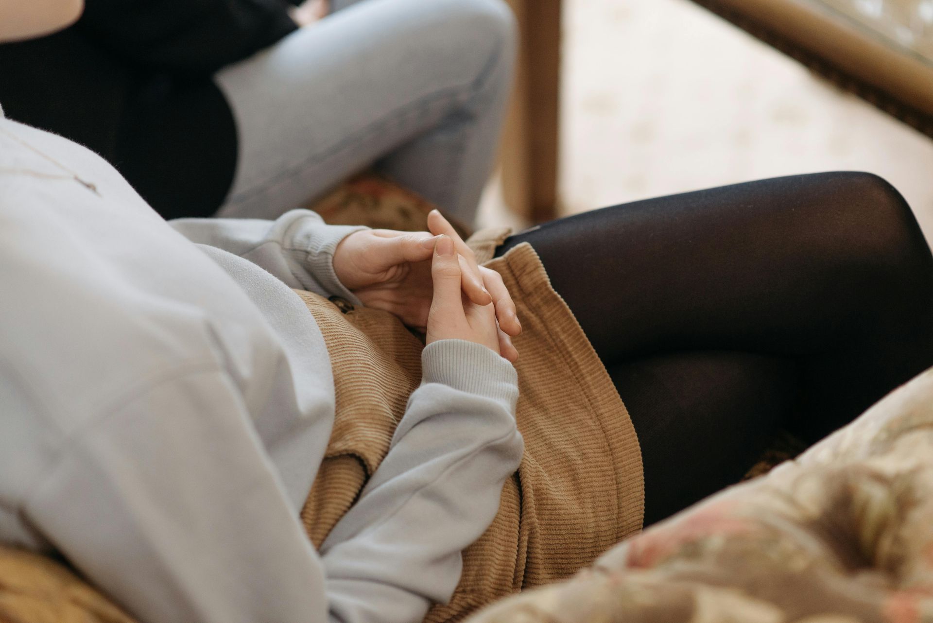 a woman folds her hands in her lap as she sets healthy boundaries during an unplanned pregnancy