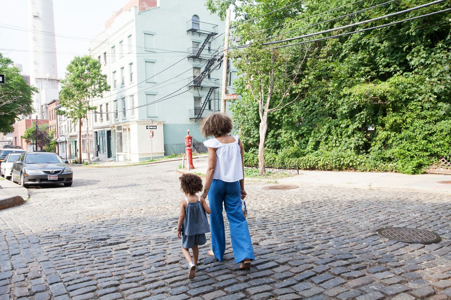 A single mom and her child walking on a cobblestone street, looking to find support.