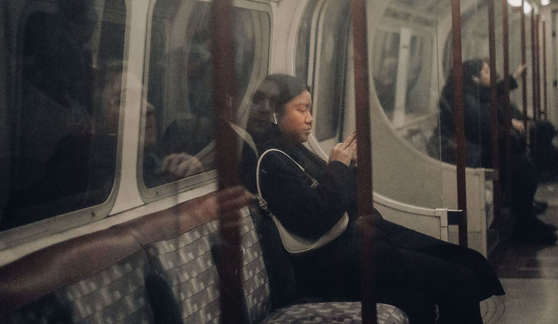 Girl sitting on a subway in New York City (NYC) on her phone processing