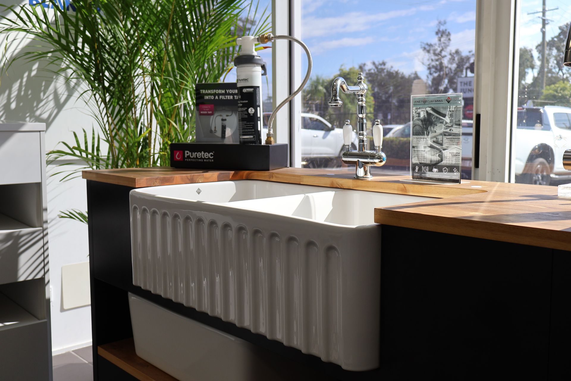 A kitchen with a large white sink and a wooden counter top.