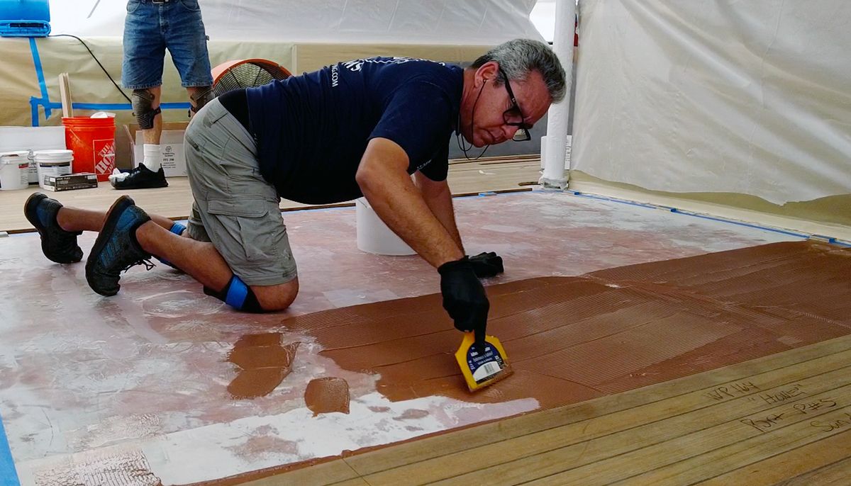 Teakdecking Systems worker on board a vessel, gluing down a deck with precision and expertise