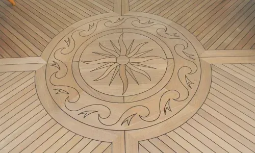 Teak decking on a yacht with an intricate custom circular design, showcasing craftsmanship and nautical elegance