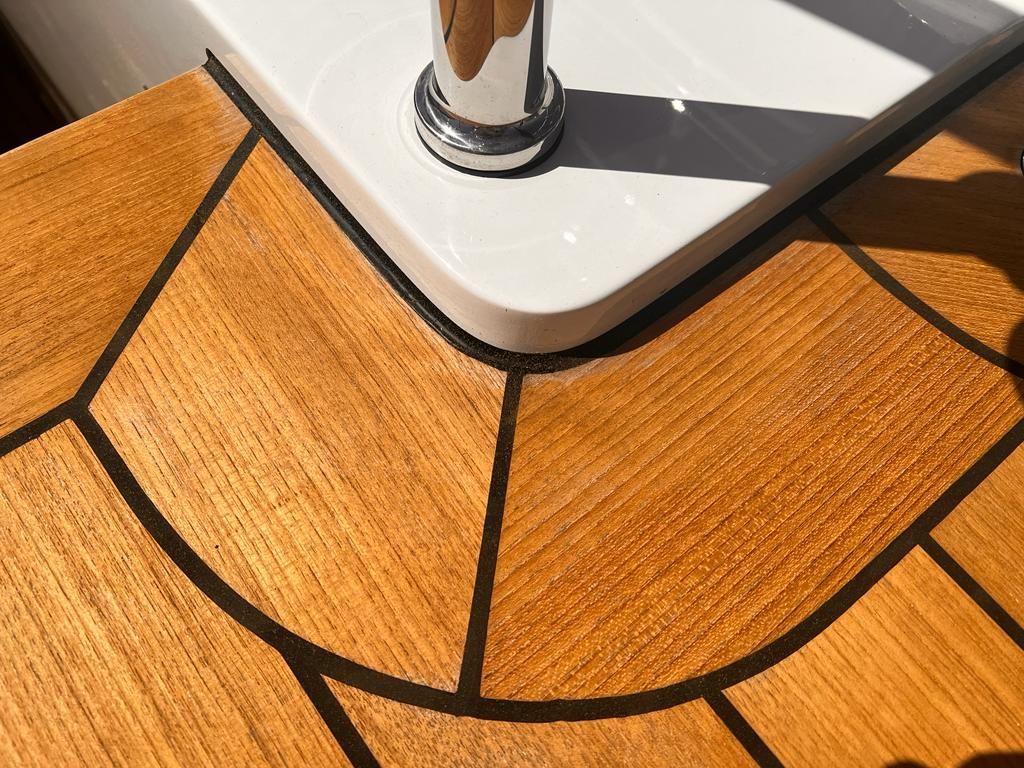 Teak decking on a yacht by Teakdecking Systems, featuring a perfectly crafted seam around a corner, showcasing precision
