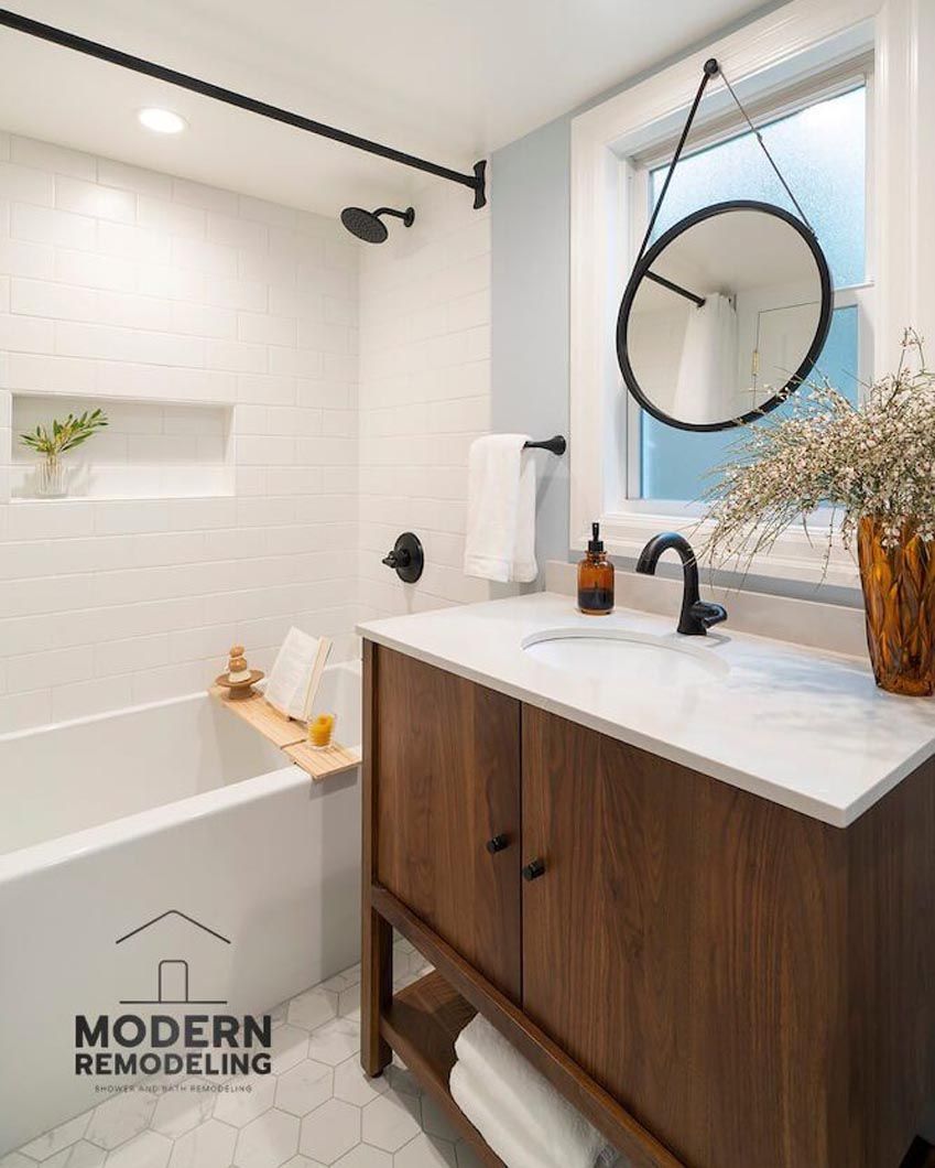 A bathroom with a sink , tub and mirror.