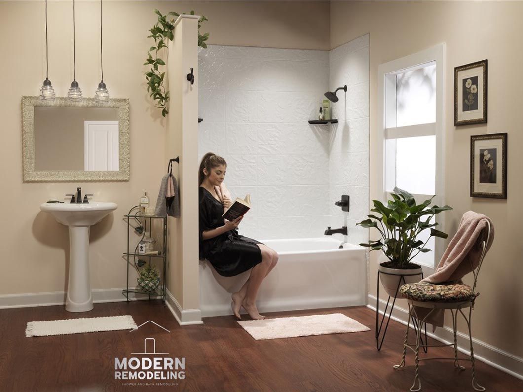 A woman is sitting on the edge of a bathtub reading a book.