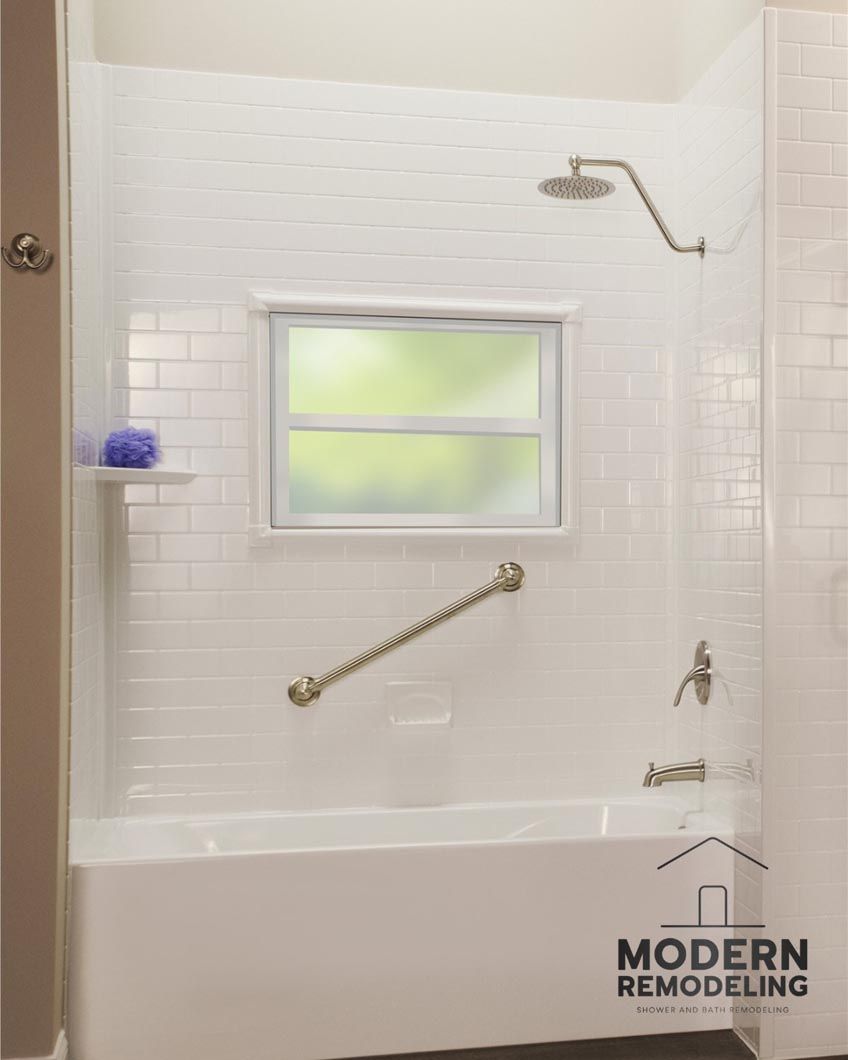 A bathroom with a bathtub , shower and window.