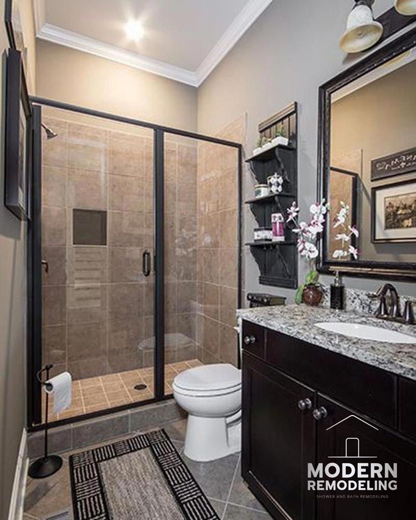 A bathroom with a toilet , sink , mirror and walk in shower.