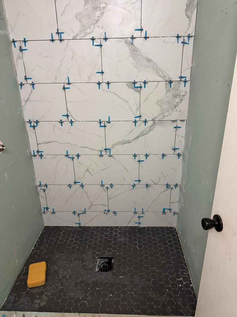 A shower stall with tiles being installed in a bathroom.