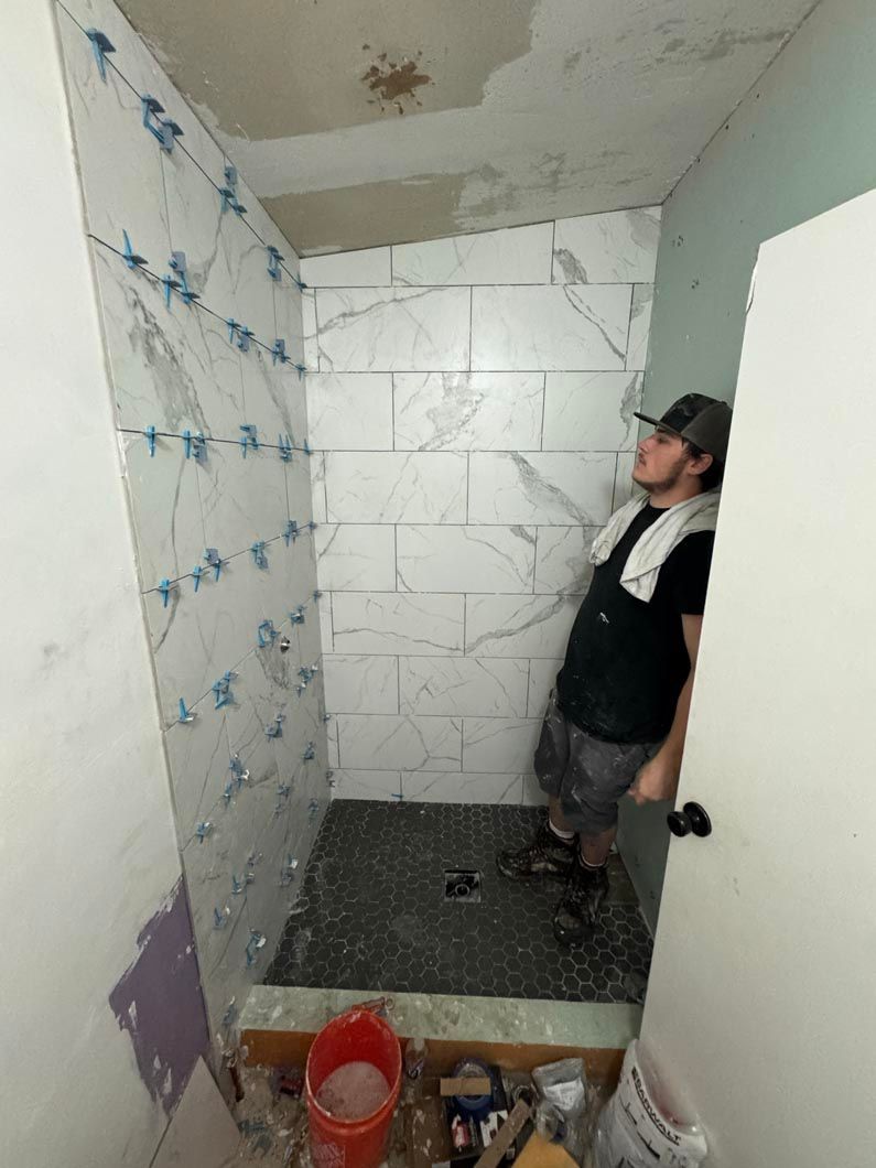 A man is standing in a bathroom under construction.