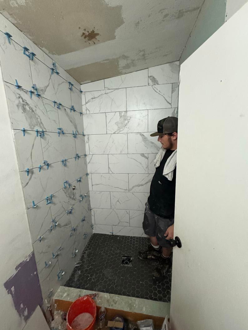 A man is standing in a bathroom under construction.