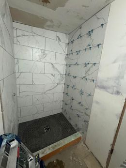 A bathroom with a walk in shower under construction.