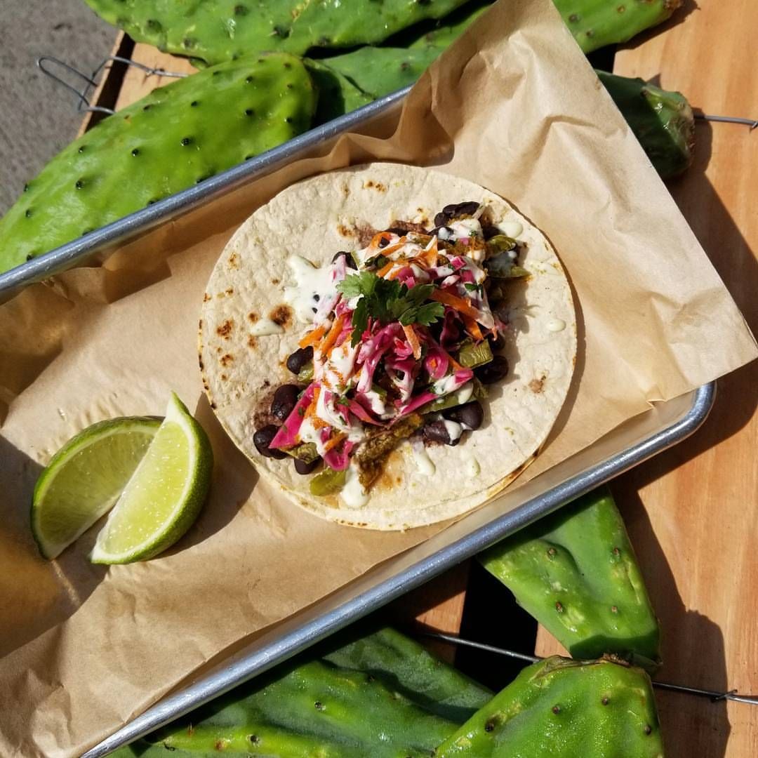A taco on a tray with a slice of lime.