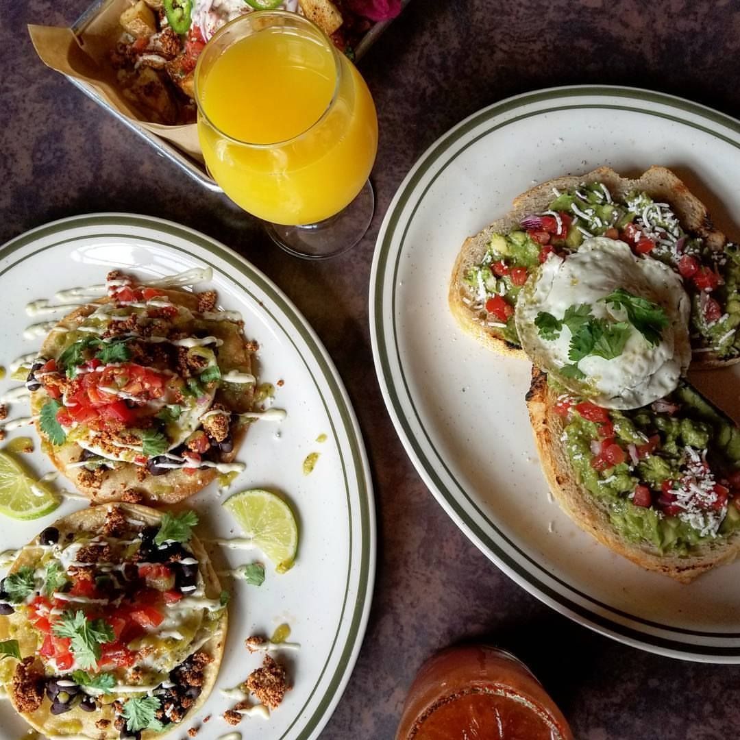 Two plates of food and a glass of orange juice on a table.