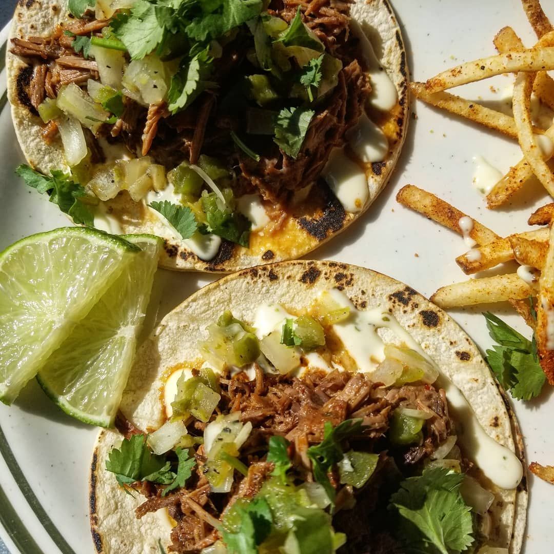 Two tacos and french fries on a white plate.
