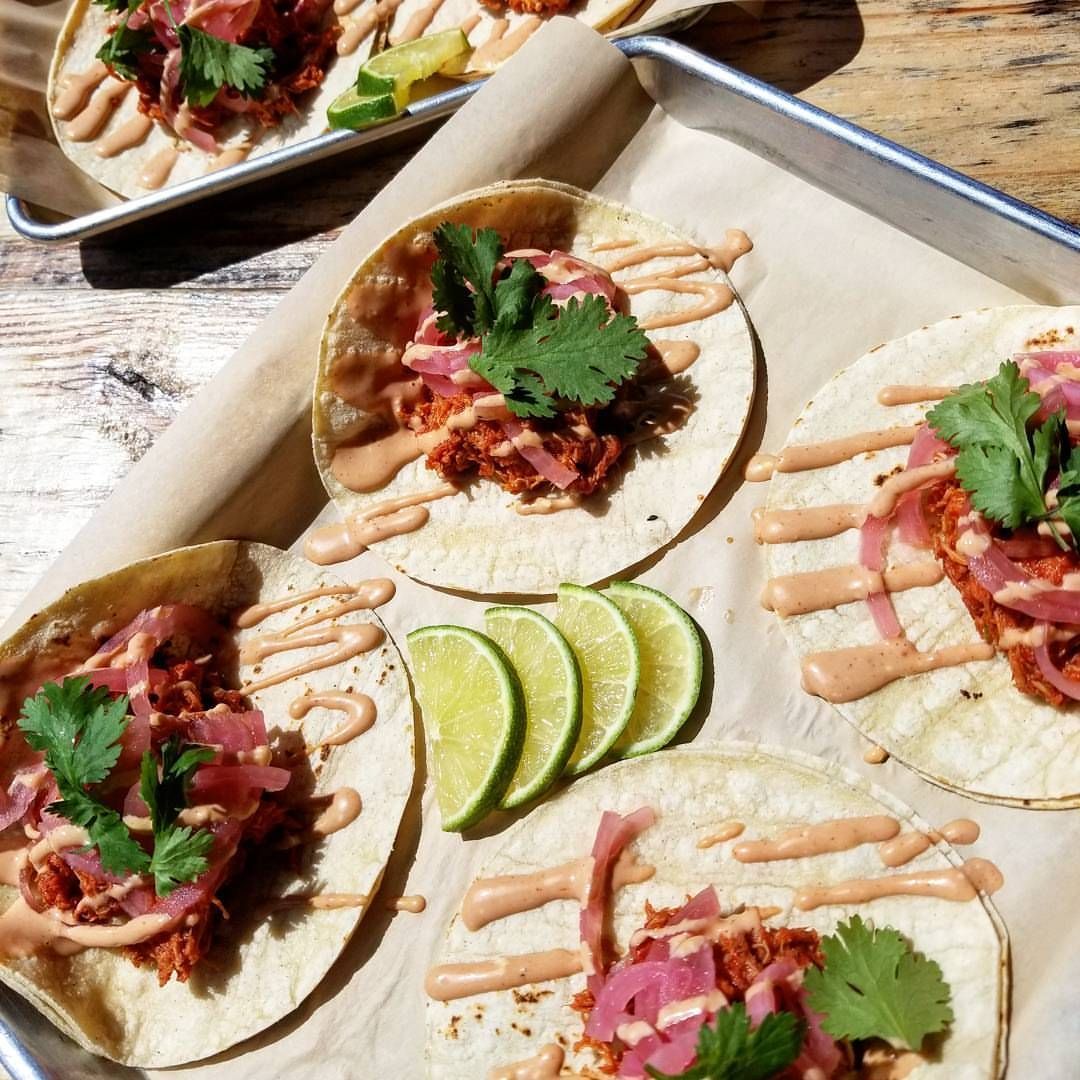 A tray of tacos with lime slices on top.