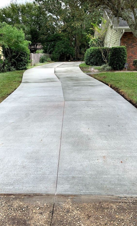 A concrete driveway leading to a house in a residential area.