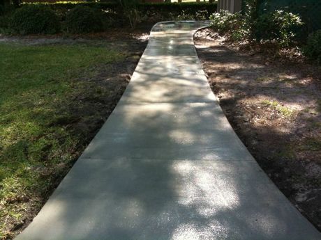 A concrete walkway is going through a grassy area.