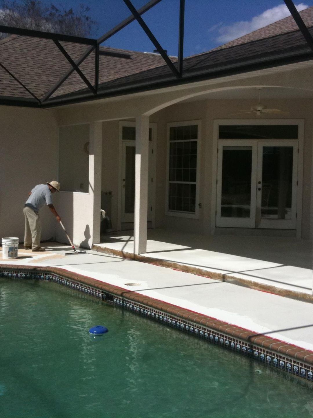 A man is painting the side of a swimming pool