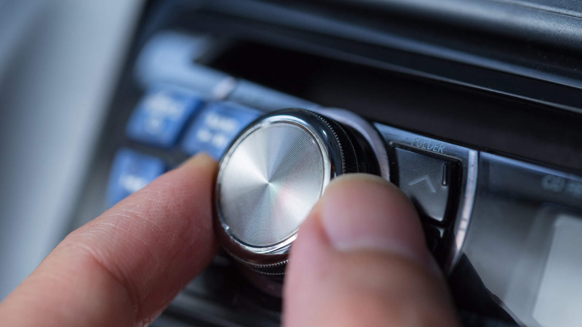 A person is adjusting the volume on a car radio.