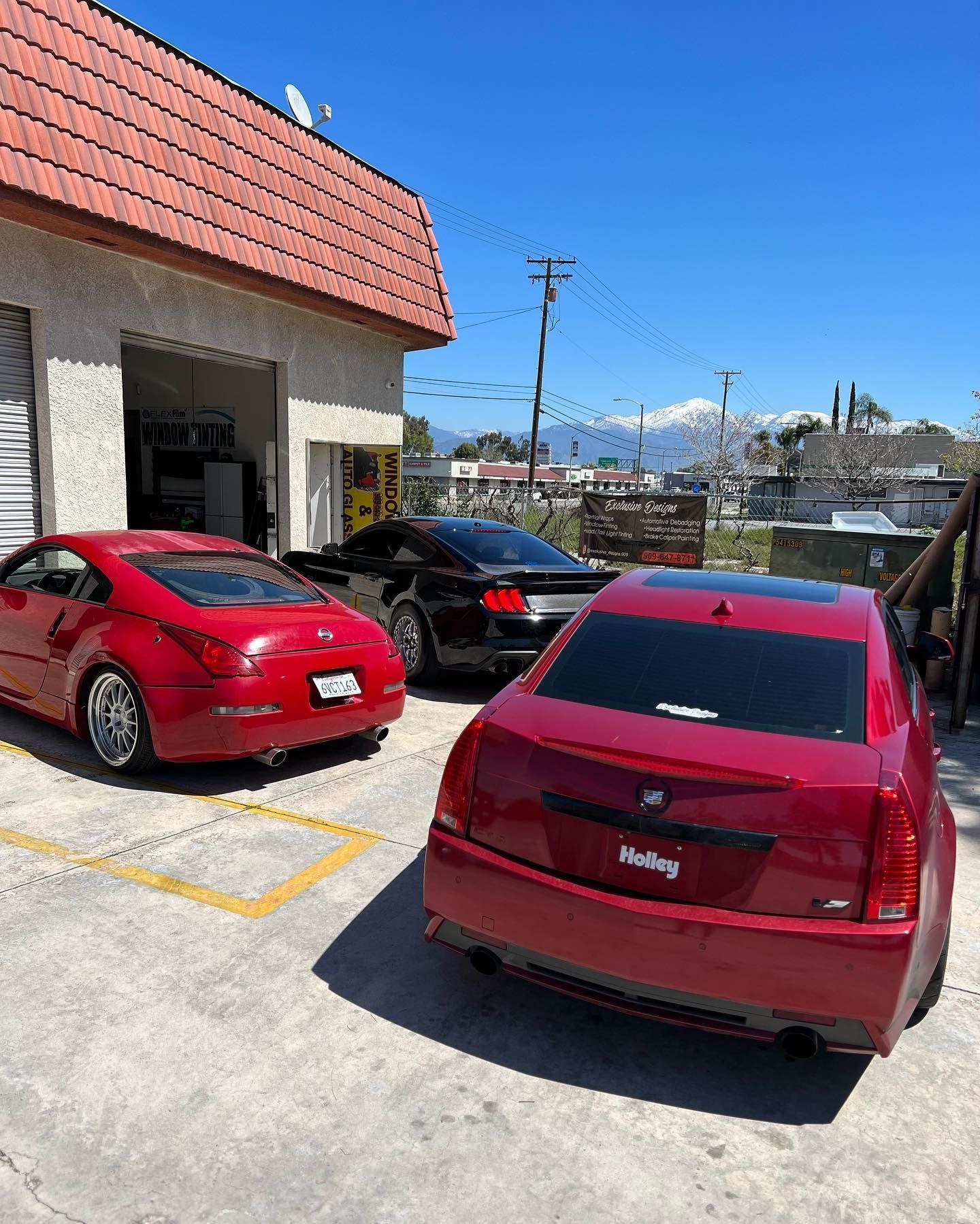 Two red cars are parked in front of a building.