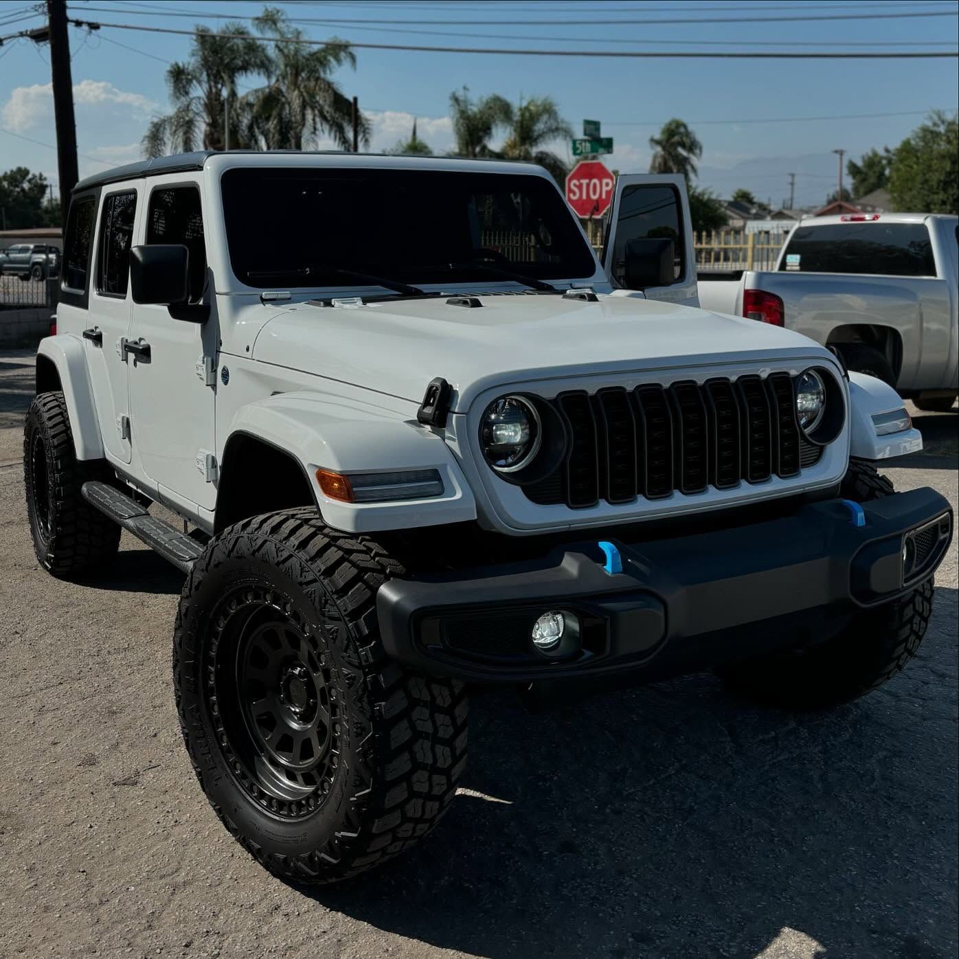 A white jeep is parked in front of a stop sign