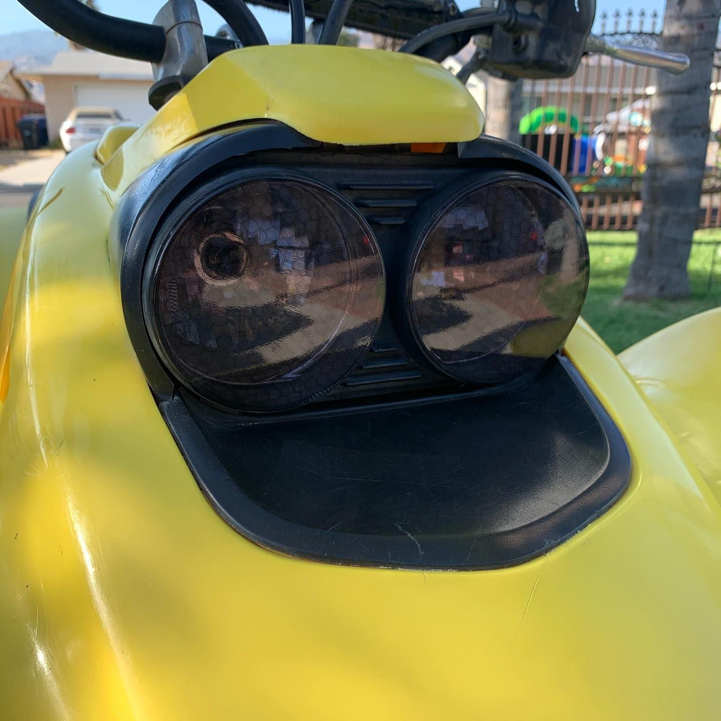 A close up of a yellow atv with the headlights on
