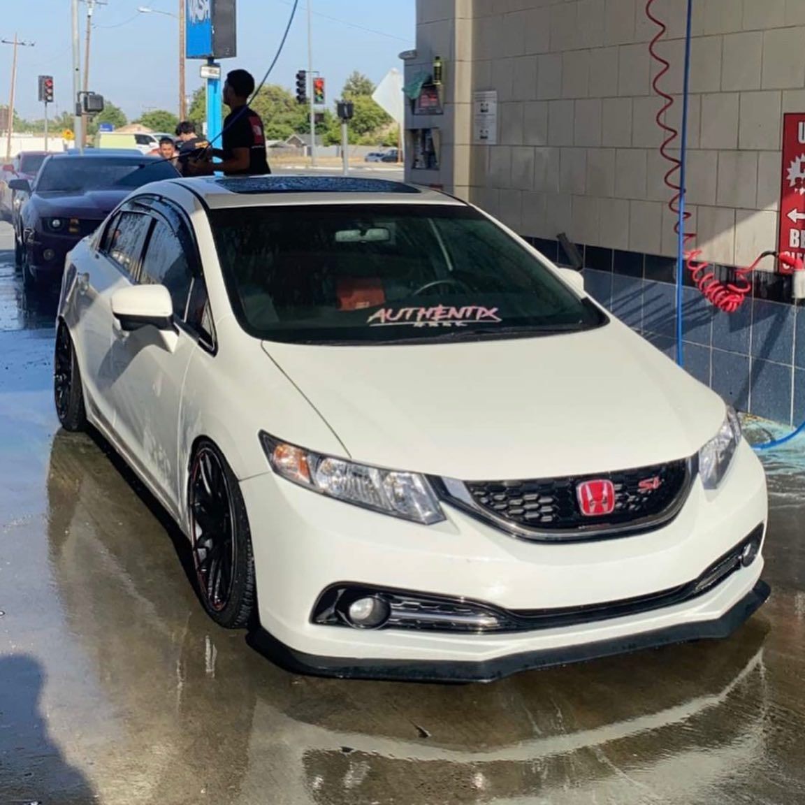 A white honda civic is parked at a car wash
